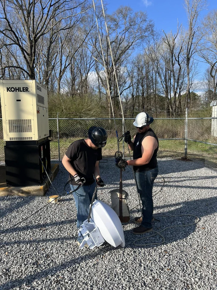 Vertical Axis crew prepping a backhaul dish on the ground at an Alabama Lightwave tower compound