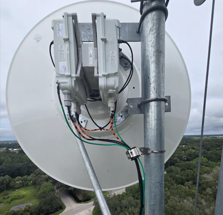SAF Integra-X carrier-grade microwave radio and dish hardware installed on a Bibb County public-safety backhaul site, labeled From 911 by the install crew