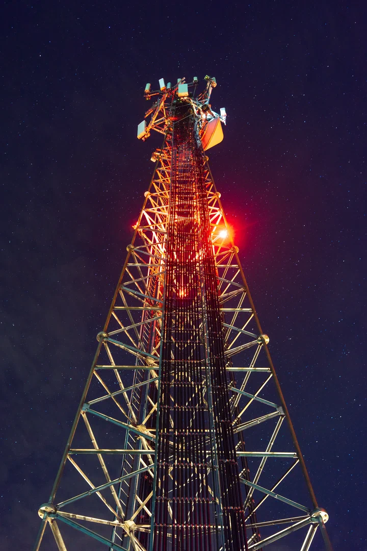 Red obstruction beacon glowing at dusk on a guyed tower