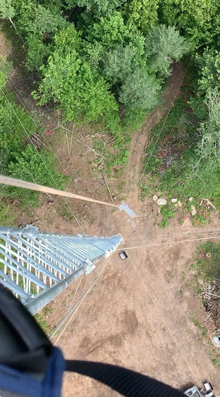 Climber using a total station to verify tower plumb