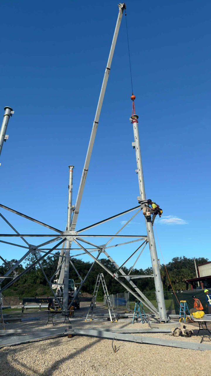 Crew erecting a utility communications tower adjacent to a substation yard